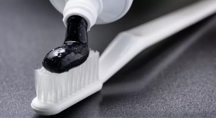 Белая зубная щетка и отбеливающая зубная паста с черным углем