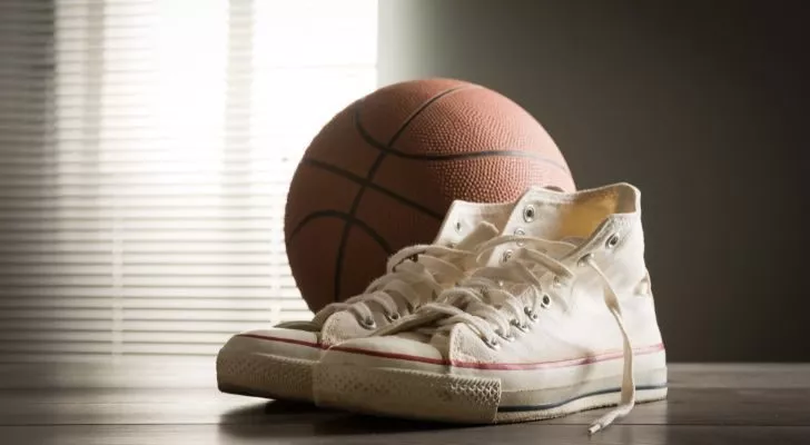 Белые кроссовки Converse с низкой посадкой лежат рядом с баскетбольным мячом