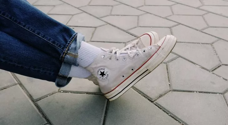 Скрещенные ноги в белых ботинках Chuck Taylor Converse