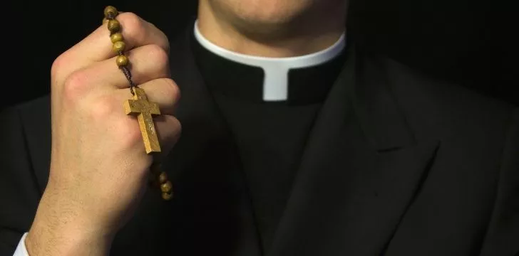 Священник держит на шее ожерелье из крестов