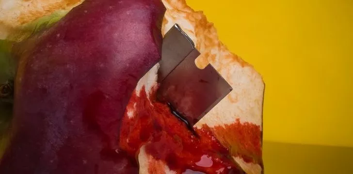 Острое лезвие бритвы внутри наполовину съеденного яблока, залитого кровью
