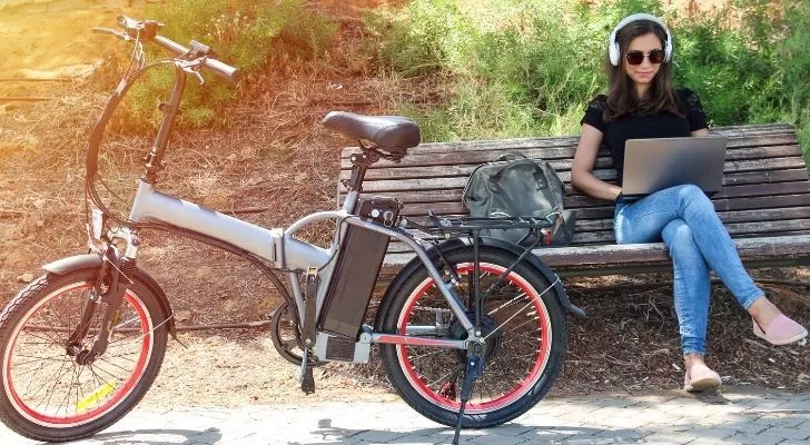 Электрический велосипед с женщиной, работающей на скамейке рядом с ним