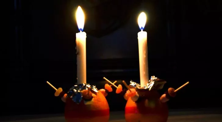 Два зажженных христослава, поставленные рядом друг с другом в темноте
