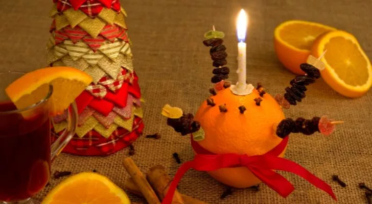 Христинка рядом с различными праздничными предметами, включая нарезанные апельсины и глинтвейн